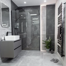 Moderní šedá koupelna s walk-in sprchou za sklem, závěsnou skříňkou s umyvadlem, černými bateriemi a černým žebříkovým radiátorem