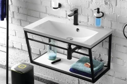 Závěsné umyvadlo v černém kovovém rámu na pozadí bílé cihlové stěny, s otevřenou policí na ručníky a doplňky