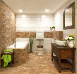 Menší rustikální koupelna s obezděnou vanou, dřevěnou skříňkou pod umyvadlem s kombinací světlých a cihlových obkladů