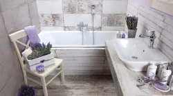 Útulná koupelna s vanou, bílým umyvadlem, dřevěnou židlí a levandulovými dekoracemi v jemných krémových odstínech