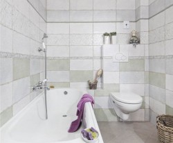 Menší koupelna s vanou, závěsným WC, světlým obkladem a levandulovými doplňky v provence stylu