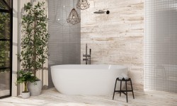 Bílá volně stojící vana u stěny v dřevodekoru, geometrická závěsná světla, černá sprchová baterie a stolička s ručníky