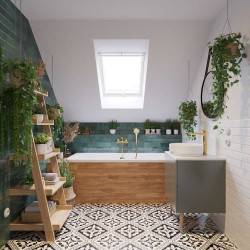 Podkrovní koupelna s vanou v dřevěném obkladu, zelenými obklady na stěně, vzorovanou dlažbou a umyvadlem se zlatou baterií; doplněné rostlinami