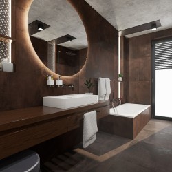 Luxusní koupelna v tmavě hnědých tónech s velkým kruhovým zrcadlem, umyvadlem na dlouhé desce a obezděnou vanou v zadní části