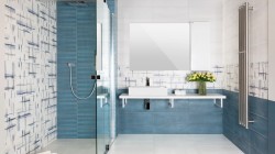 Moderní modrá koupelna s walk-in sprchou, bílým závěsným pultem s hranatým umyvadlem a velkým zrcadlem