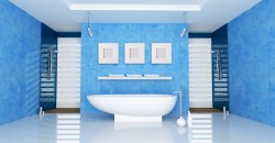 Minimalistická koupelna v modrých tónech s volně stojící oválnou vanou uprostřed a dvěma sprchovými kouty