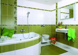 Koupelna s rohovou vanou, zelenými obklady a svislými květinovými pásy, závěsným WC a umyvadlem se zrcadlovou skříňkou