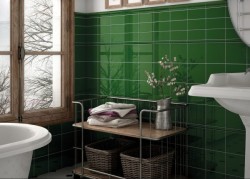 Vintage koupelna s lesklými zelenými obklady, oknem v dřevěném rámu, vanou a drátěným regálem s košíky