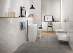 Moderní koupelna s šedou dlažbou, vysokým umyvadlem, závěsným WC a bidetem; dřevěná police a černé závěsné světlo