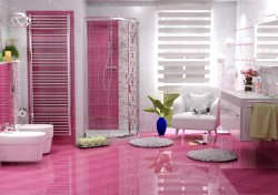 Výrazně růžová koupelna s lesklou dlažbou, rohovým sprchovým koutem, bílým křeslem a dvojicí umyvadel na dlouhé skříňce