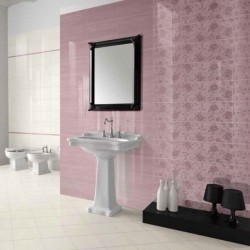 Koupelna s umyvadlem na sloupu, černým ozdobným rámem zrcadla a růžovým obkladem s jemným květinovým vzorem