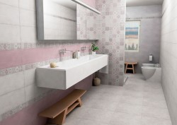 Úzká koupelna s dlouhým žlabovým umyvadlem, růžovým obkladem, patchworkovým dekorem a WC s bidetem