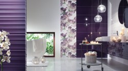 Luxusní koupelna s tmavě fialovými lesklými obklady, květinovým panelem, závěsnými skleněnými svítidly a odkládacím vozíkem se svíčkami