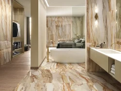 Moderní koupelna s výrazným mramorovým dekorem v teplých tónech, volně stojící vanou a zlatou stojánkovou baterií u vany