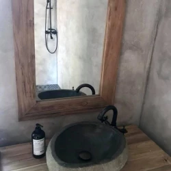 Koupelna s kamenným umyvadlem, dřevěným rámem zrcadla a sprchou se stěnami v betonové stěrce