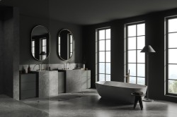 Luxusní tmavá koupelna s dvojicí kamenných umyvadel, oválnými zrcadly a volně stojící vanou před vysokými okny