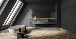 Minimalistická podkrovní koupelna s tmavými obklady, volně stojící oválnou vanou u střešního okna a dlouhou skříňkou se dvěma umyvadly
